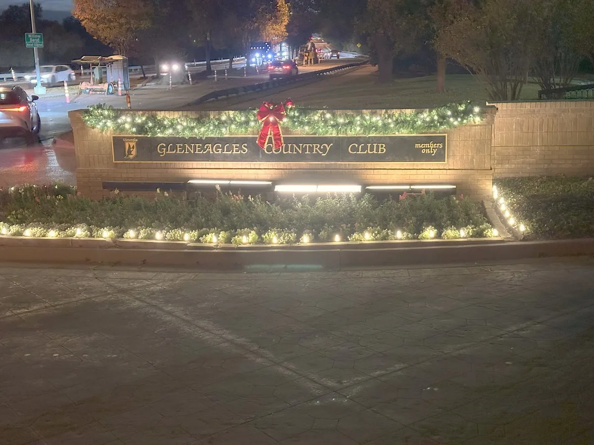 Club entrance monument with lit garland and a bow, installed by South Custom Lighting in North Texas