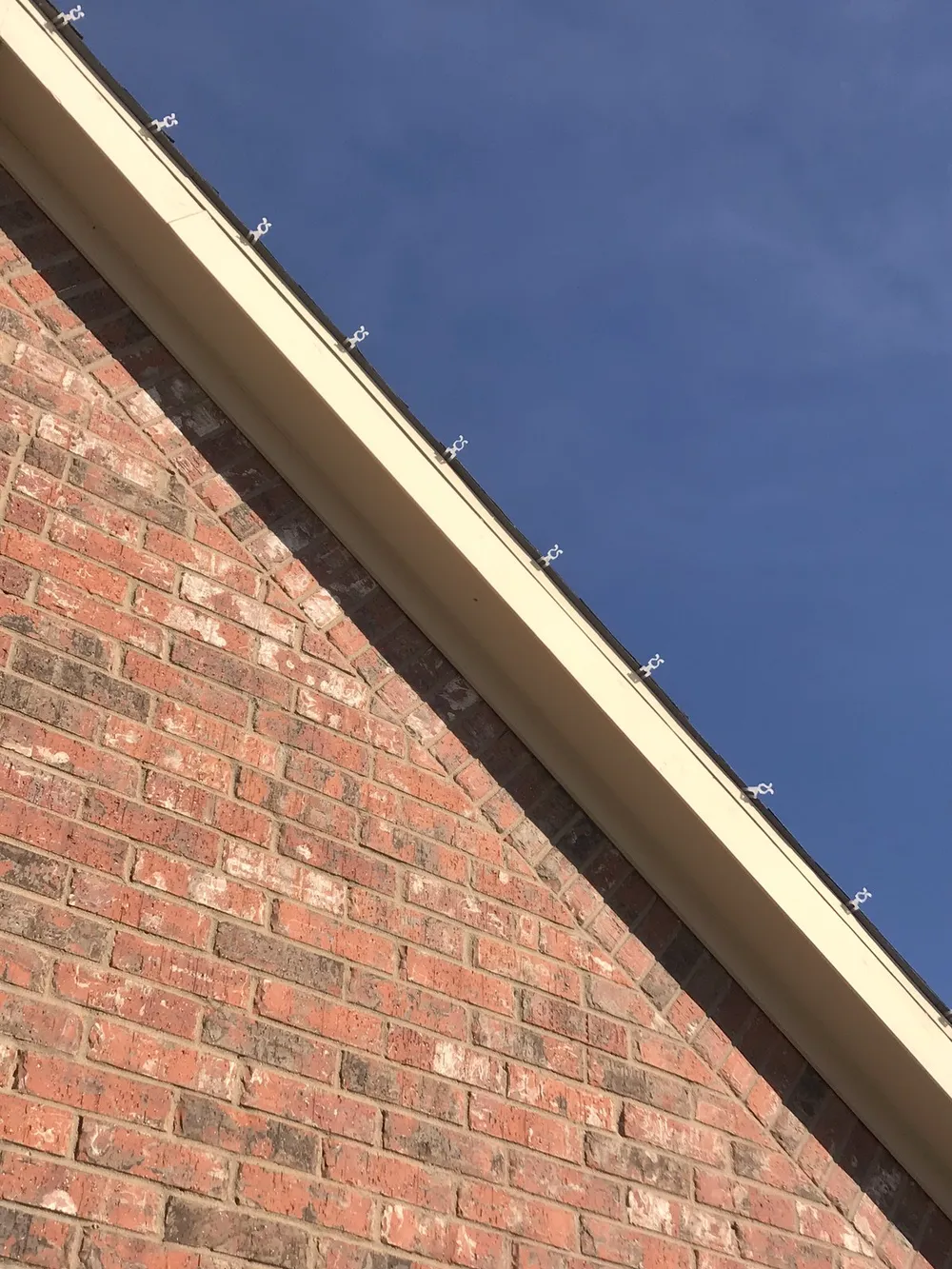 A roofline clip on brick, the attachment that comes off cleanly in January
