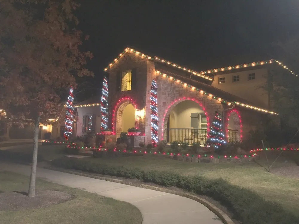 A North Texas home lit in colored permanent architectural lighting at night